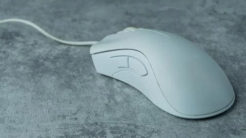 A white computer mouse is placed on a gray table with a concrete texture Stock Photos