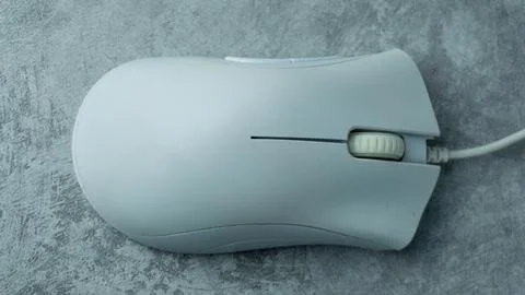 A white computer mouse is placed on a gray table with a concrete texture Stock Photos