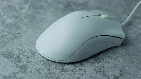 A white computer mouse is placed on a gray table with a concrete texture Stock Photos