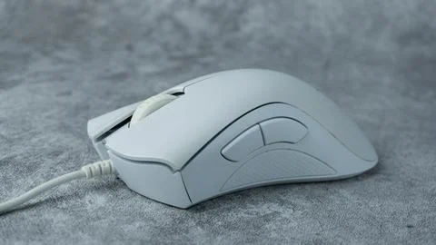 A white computer mouse is placed on a gray table with a concrete texture Stock Photos