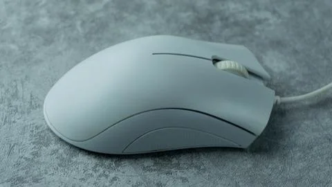 A white computer mouse is placed on a gray table with a concrete texture Stock Photos