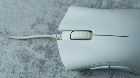 A white computer mouse is placed on a gray table with a concrete texture Stock Photos