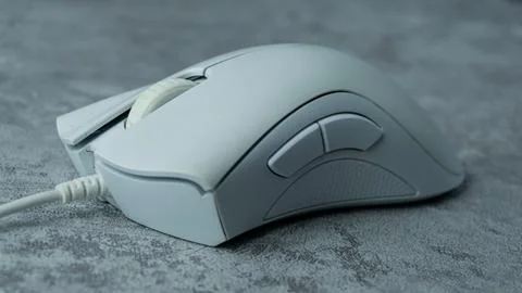 A white computer mouse is placed on a gray table with a concrete texture Stock Photos