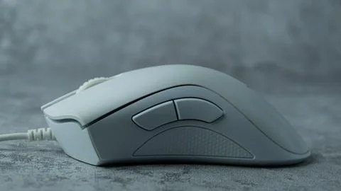A white computer mouse is placed on a gray table with a concrete texture Stock Photos