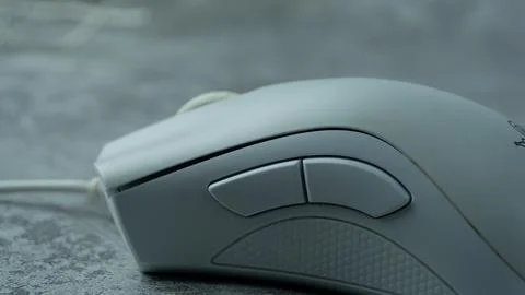 A white computer mouse is placed on a gray table with a concrete texture Stock Photos