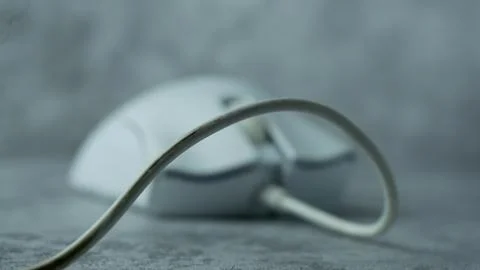 A white computer mouse is placed on a gray table with a concrete texture Stock Photos
