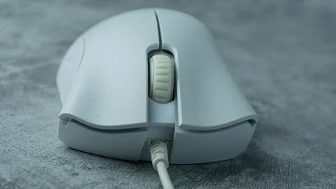 A white computer mouse is placed on a gray table with a concrete texture Stock Photos