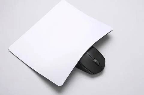 White computer mouse under a white square pad on gray surface 스톡 사진