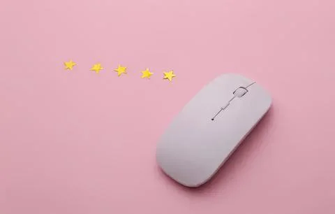 White computer mouse with yellow star decorations on pink background 스톡 사진