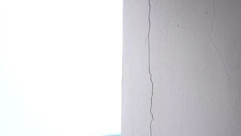 A white concrete wall corner showing a prominent vertical crack along Stock Footage 344704230