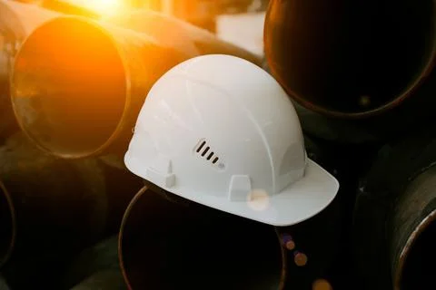 White construction helmet is lying on the pipe Stock Photos