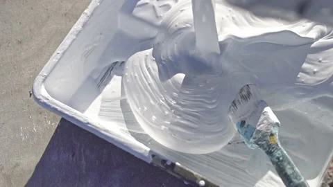 White construction paint is poured into a paint tray. Outdoors. Slow motion Stock Footage 220072413