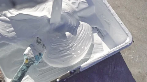 White construction paint is poured into a paint tray. Outdoors. Slow motion Stock Footage 220645897
