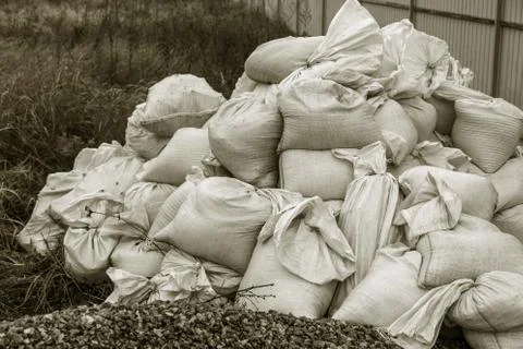 White construction sacks of construction waste are dumped in heap near fence  Stock Photos