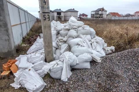 White construction sacks of construction waste are dumped in heap near fence  Stock Photos