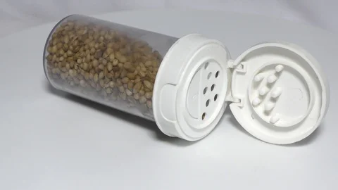 A white container filled with coriander seeds on white Stock Footage 111887945