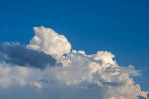 White contrasting clouds backlit by the sun on a blue summer sky. Background. Stock Photos