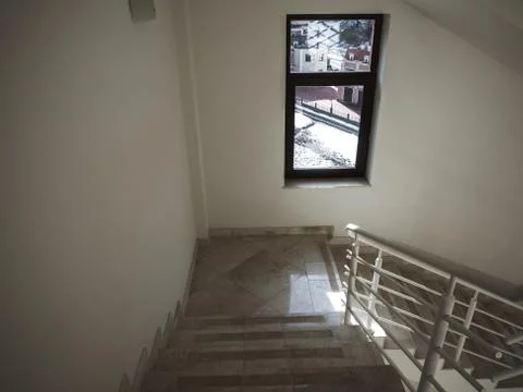 White corridor with beige marble steps, white railings and black framed window. Stock Photos