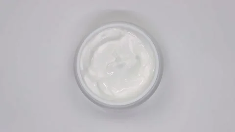 White cosmetic cream in a jar rotates on a white background Stock Footage
