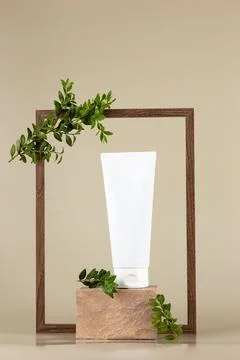 White cosmetic tube, stands on a rectangular beige stone Stock Photos