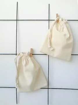 A white cotton pouch hangs on a stand with clothespins on the wall Foto stock