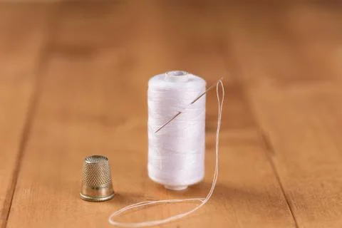 White cotton thread bobbin with needle close up Stock Photos