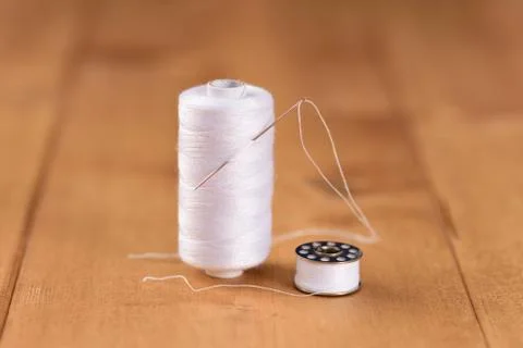 White cotton thread bobbin with needle close up Stock Photos