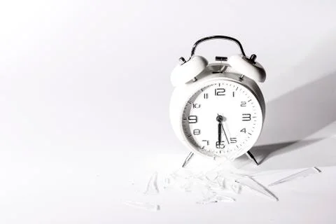 White crashed alarm clock and shards of glass on white background. Foto stock