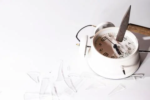 White crashed alarm clock, shards of glass and hammer on white background. Stock Photos