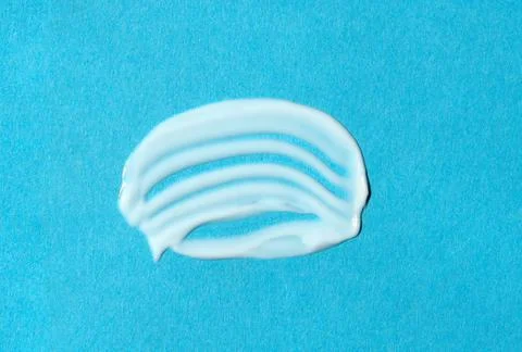 White cream sample on blue background. Smear of moisturizer closeup. Top view Stock Photos