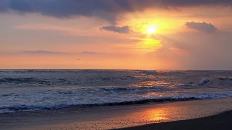 White-crested ocean waves illuminated by orange setting sun break on sand shore Stock Footage 73124945