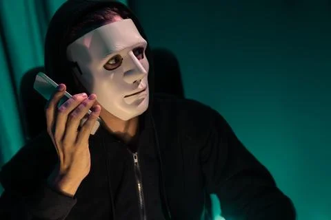 White criminal anonymous mask calling to IT owner to threaten ransom. Pecuniary. Foto stock