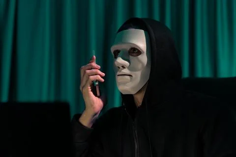 White criminal anonymous mask calling to IT owner to threaten ransom. Pecuniary. Foto stock