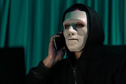 White criminal anonymous mask calling to IT owner to threaten ransom. Pecuniary. Stock-Fotos