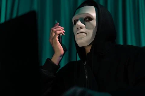 White criminal anonymous mask calling to IT owner to threaten ransom. Pecuniary. Stock-Fotos
