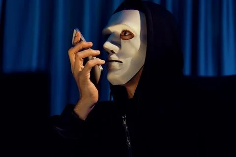 White criminal anonymous mask calling to IT owner to threaten ransom. Pecuniary. Stockfoto's