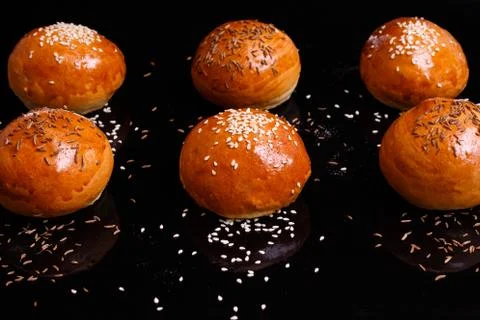 White crispy buns with sesame seeds. Photo on a black background. Stock Photos