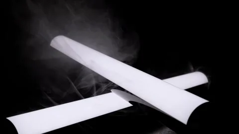 White Crossed Cylinders With Swirling Smoke Against Dark Black Background Stock-Footage 332664553