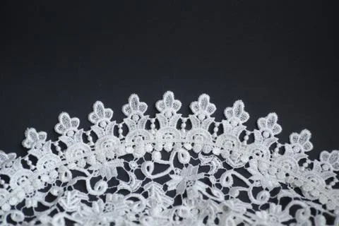 White crotcheted lace pattern on dark background as wallpaper Stock Photos