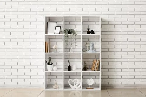 White cube bookshelf with decorative items and plants against a modern brick  Stock Photos