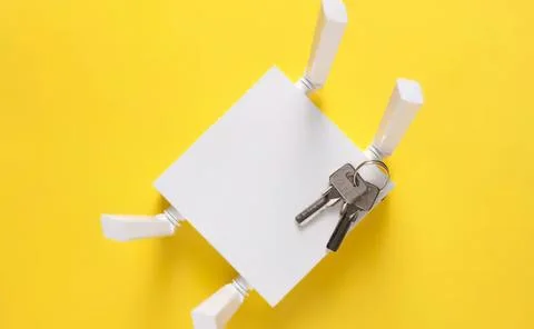 White cube-shaped robot with keys on yellow background 스톡 사진