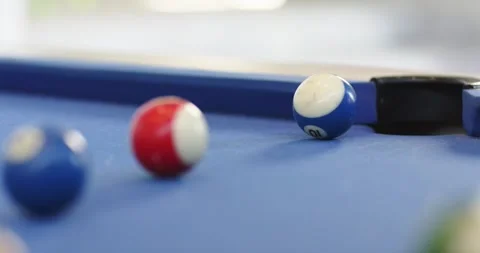 White cue ball entering frame, rolling on pool table toward red striped ball to Stock Footage 338167723