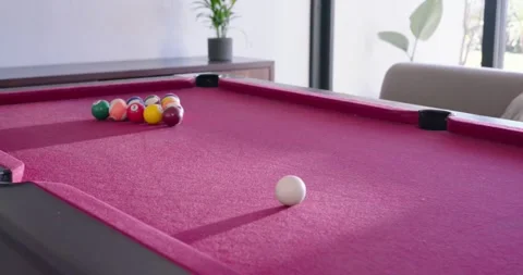 White cue ball is rolling slowly across magenta felt pool table toward racked Stock Footage 337745260