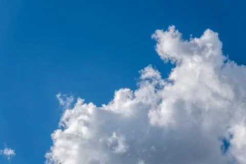 White cumulus cloud standing out against a bright blue sky Stock Photos