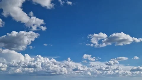 White cumulus clouds against a bright blue sky Stock Footage 345341215