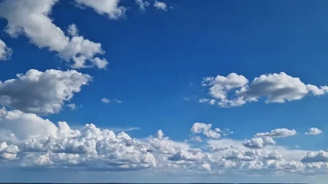 White cumulus clouds against a bright blue sky Stock Footage 345341224