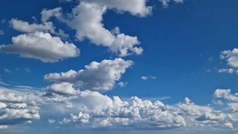 White cumulus clouds against a bright blue sky Stock Footage 345341244