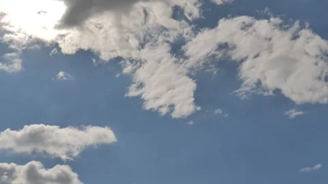 White Cumulus Clouds and Aircraft Contrail Drifting Across a Bright Blue Sky Stock Footage 346140107