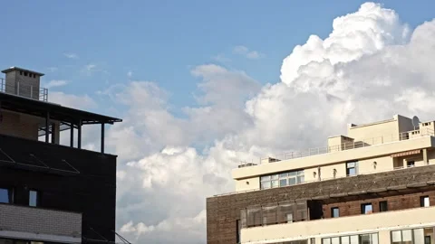 White cumulus clouds on the blue sky over the roofs of residential buildings Stock Footage 276442943