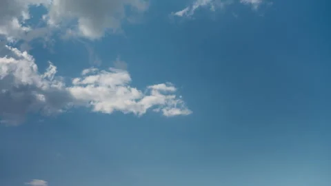 White cumulus clouds drift across a clear blue sky with copy space for text Stock Footage 340039738